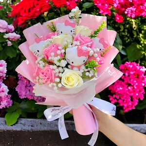 Hello Kitty bouquet with pink and white artificial flowers, wrapped in pale pink paper