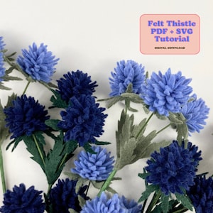 Felt thistle flower craft with blue layered blooms and green leaves
