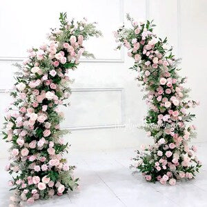 Artificial flower archway with pale pink blooms and green leaves, wedding decor