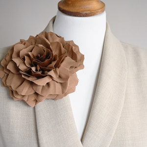 Fabric flower brooch with layered brown beige petals pinned to a light shirt