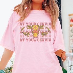 Pink graphic T-shirt with floral print and slogan text across the chest