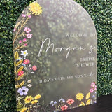 Round acrylic bridal shower welcome sign with colorful floral border and text 'Welcome to Morgan's'