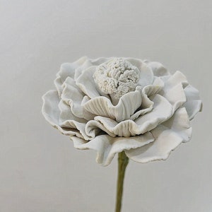 Handmade ceramic flower with layered white petals on a slender stem