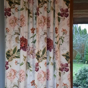 Pink and ecru floral curtain with rose-and-bloom pattern, hanging with pleats