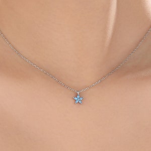 Tiny aquamarine blue CZ flower pendant necklace on a silver chain