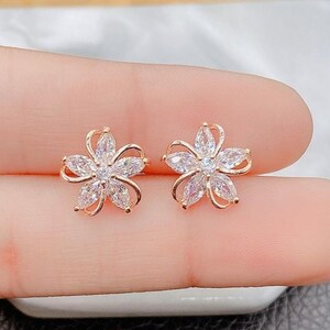 Gold-tone cubic zirconia flower stud earrings with five petal sparkle stones
