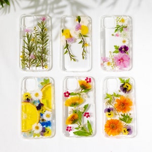 Pressed flower phone cases, clear with colorful pressed blooms in assorted layouts