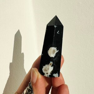 Black flower agate crystal tower with white inclusions, faceted obelisk point