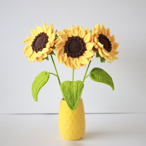 Crochet sunflower pattern featuring yellow flowers with dark centers in a small vase
