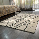 Cream wool area rug with dark abstract branch pattern, rectangular