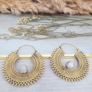 Gold large hoop earrings with ornate mandala detailing and a pale moonstone-like center