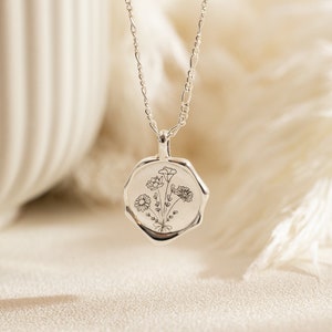 Round silver pendant necklace with engraved floral family design on a fine chain