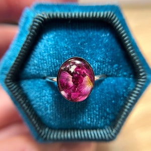Oval memorial flower ring with purple-pink dried flower in glass bezel