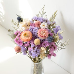 Dried flower bouquet in a clear vase with purple, pink, and yellow blooms