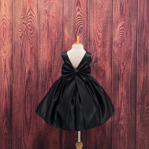 Black satin flower girl dress with bow detail and V-back, knee-length