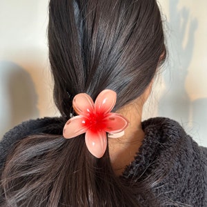 Plumeria flower hair claw clip with pink peach petals, on dark hair