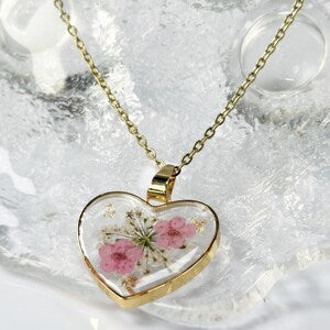 Gold heart pendant necklace with clear glass center and pressed pink and flower petals