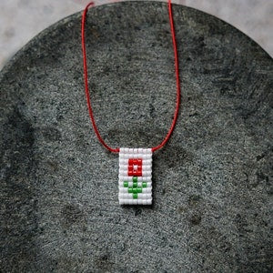 Red string flower charm necklace with beaded flower pendant