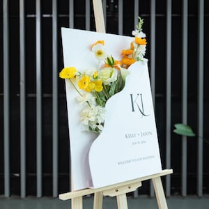 White welcome sign on easel with yellow and white floral decorations
