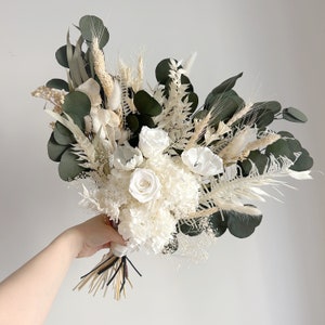 Boho bridal bouquet with white roses, dark green leaves, and dried pampas grass