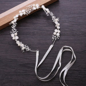 White floral bridal headband with pearl-like blossoms and satin ribbon ties