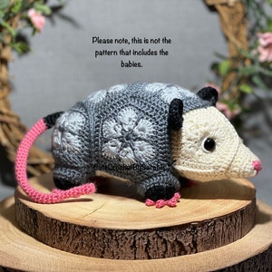 Crochet opossum plush toy with gray body, cream face, black ears, pink tail