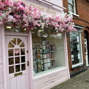 Pink cherry blossom flower garland draped over a shop window frame