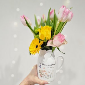 Personalized ceramic flower vase with printed message, held with pink and yellow tulip bouquet
