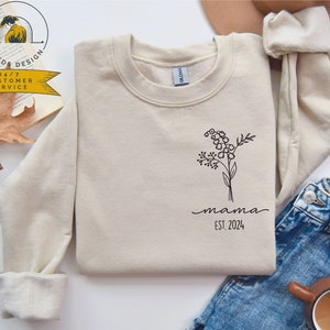Cream long-sleeve sweatshirt with floral tree graphic and EST. 2024 print
