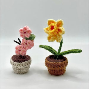 Crocheted potted cherry blossom and daffodil flowers in mini knit pots