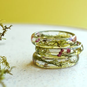 Stacked resin rings with dried moss and pressed flowers in a clear band