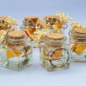 Customized wedding favor candle in clear glass jar with dried flowers and rustic lid