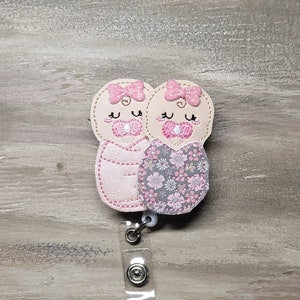 Pink and gray floral baby swaddle with two stitched cartoon faces