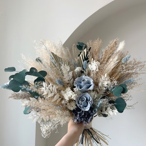 Dusty blue dried bridal bouquet with blue roses, white pampas, and green eucalyptus leaves