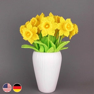 Crocheted daffodil bouquet with yellow blooms, green leaves, in a white ribbed vase