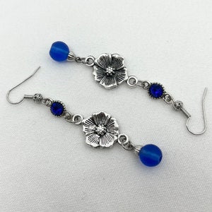 Silver flower dangle earrings with blue glass bead accents