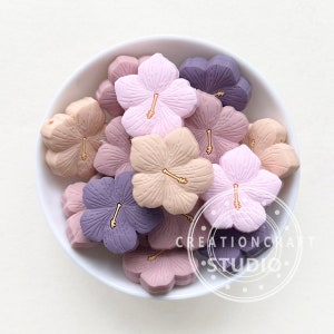 Pastel flower-shaped beads with gold-tone loop centers in a round tray