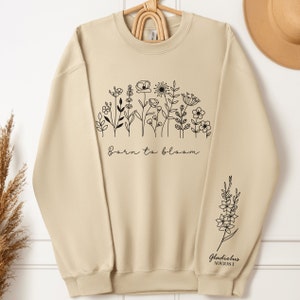 Cream crewneck sweatshirt with black birthflower line-art on chest and sleeve