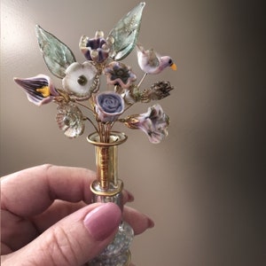 Miniature glass flower bouquet with purple, white, and clear blooms in a gold vase