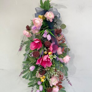 Artificial wall hanging flower garland with pink and purple blooms and green leaves