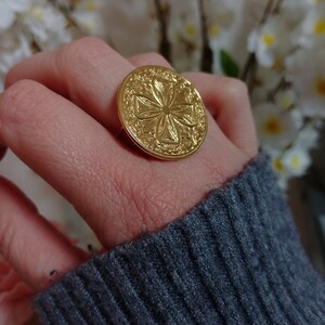 Gold adjustable flower engraved ring, round face on hand