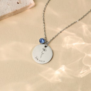 Silver-toned necklace with round disc pendant and small blue birthstone charm