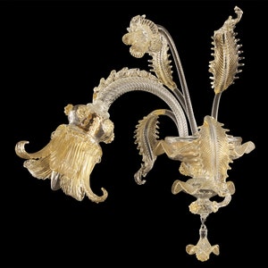 Gold-tone decorative wall sconce with ornate curved arms and dangling glass accents