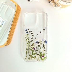 Transparent phone case with pressed small purple and blue flowers in vertical arrangement