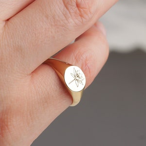 Gold-tone birth flower ring with small circular pendant on slim band