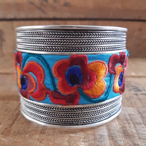 Adjustable embroidered cuff with blue floral pattern and silver braided trim