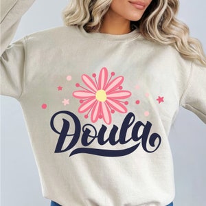 Light beige t-shirt with pink flower and 'Doula' text graphic