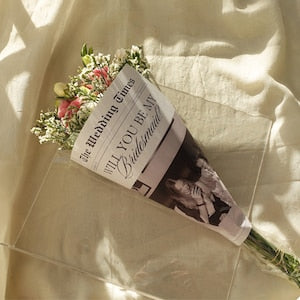 Flower bouquet with printed newspaper wrap in white and dark lettering