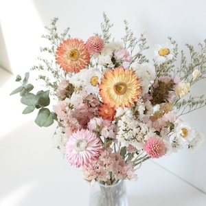 Pastel dried flower bouquet with peach, blush, and white blooms in a glass vase