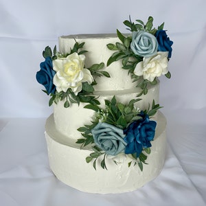 Dusty blue and ivory floral cake topper set with roses and greenery on cake